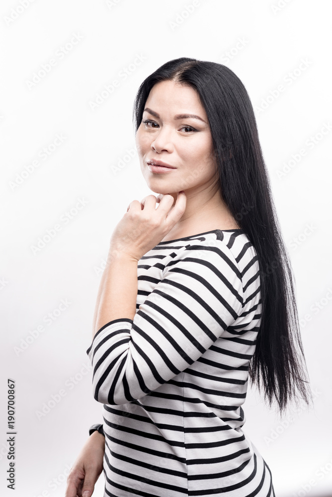 Delicate beauty. Gorgeous young woman with long dark hair standing half-turned posing for the camera while standing isolated on a white background Delicate beauty. Gorgeous young woman with long dark hair standing half-turned posing for the camera while standing isolated on a white background