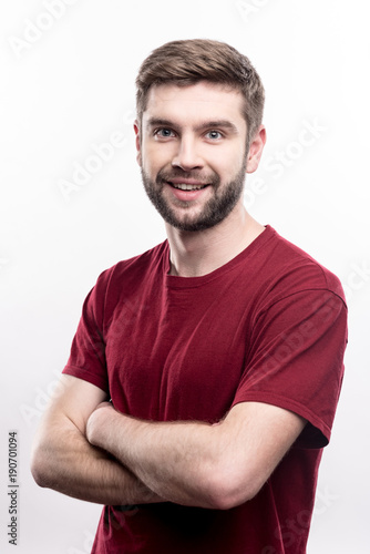 Great mood. Upbeat young man folding his arms across his chest and smiling at the camera while posing isolated on a white background