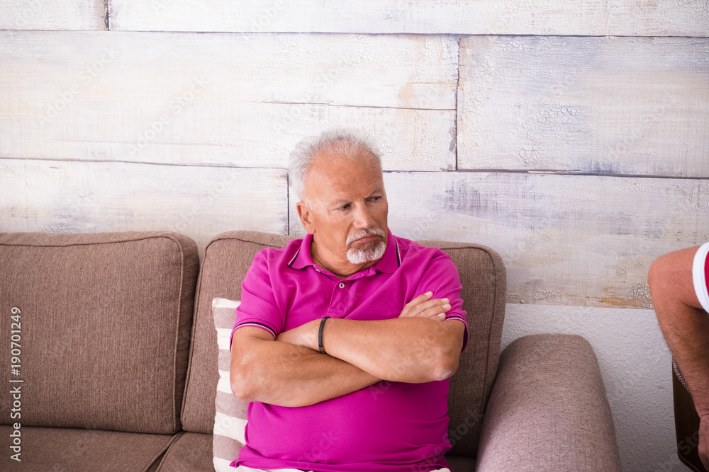 man sitting on brown couch with folded arms with purple shirt reflects pensive man sitting on brown couch with folded arms with purple shirt reflects pensive
