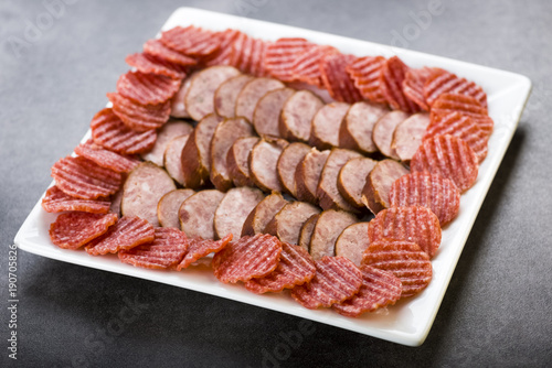 a plate of sliced cold meats - delicious smoked sausage and spicy salami - a photo in a rustic style.