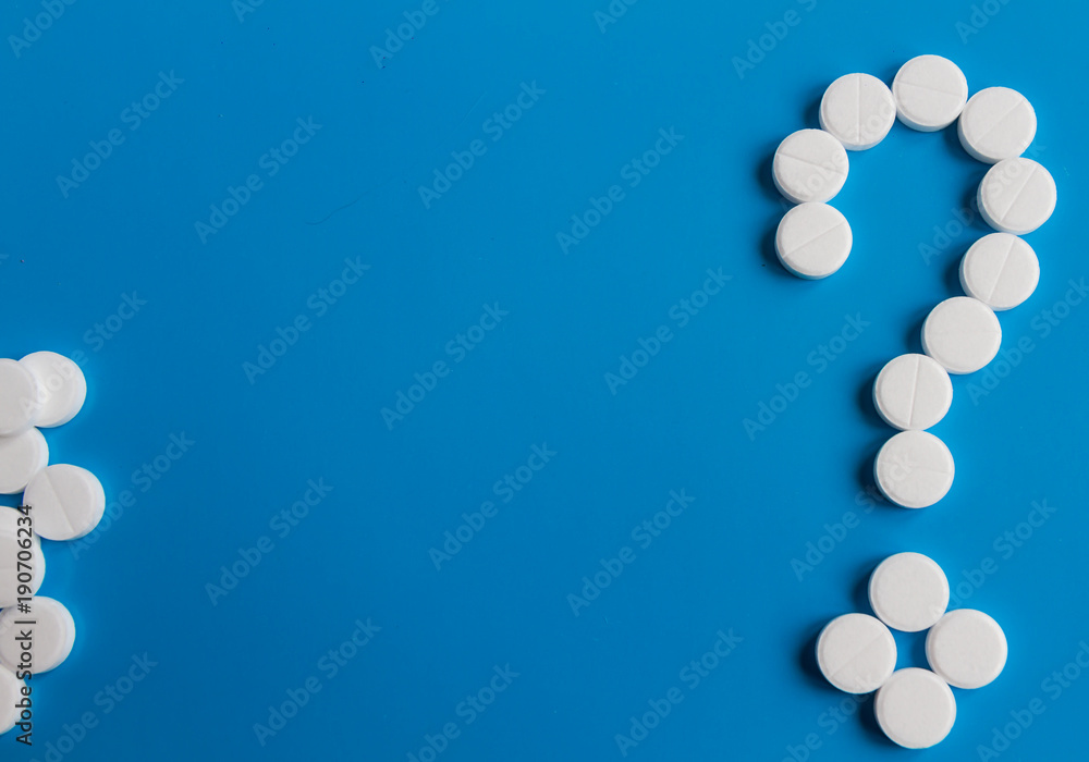 White medical pills question mark on blue background, conceptual image. Medications for the treatment of patients White medical pills question mark on blue background, conceptual image. Medications for the treatment of patients