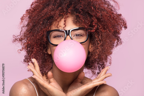 Afro girl blowing bubble gum balloon. photo