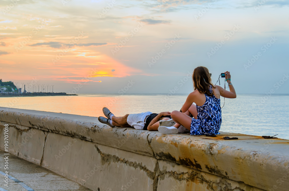 Φωτογραφία Young couple watching and photographing the sunset on the ocean