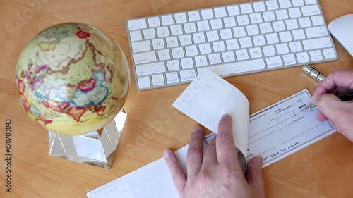 Top shot of bsiness man writing a cheque with globe spinning inside office photo