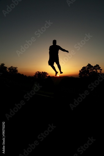 silhouette of a man jumping on background of sunset