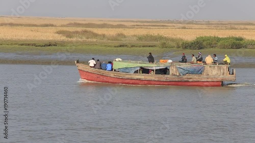 SITTWE, MYANMAR - JANUARY 29, 2016: Unidentified local people in wooden boat on the river water from the town of Mrauk-U to Sittwe during dawn. Burma photo