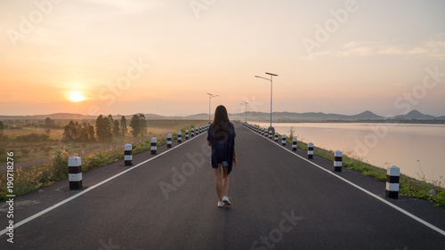 Young asian woman walking on the road at sunrise