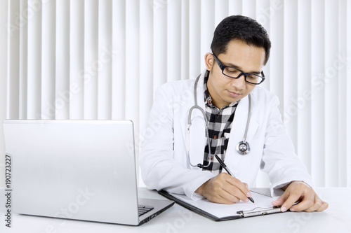 Male doctor writing a report