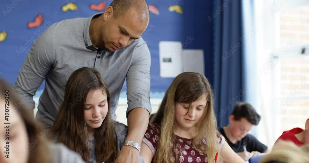 4k, A teacher helping his students with their work in the classroom. 4k, A teacher helping his students with their work in the classroom.
