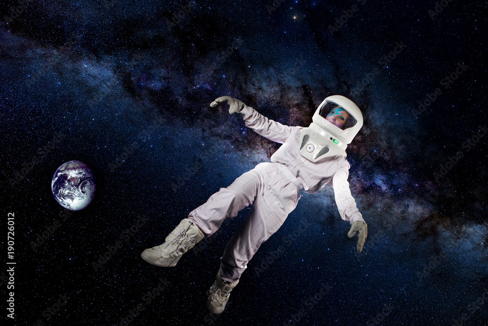 Astronaut in space, in zero gravity on the background of the starry sky, galaxy, and planet earth. Elements of this image furnished by NASA.