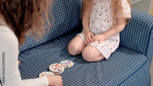 A girl collects toys in a box sitting on the floor at home dobble photo