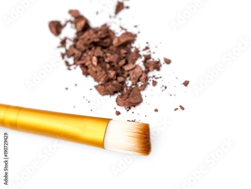 Makeup brush with crushed eye shadows on white background.