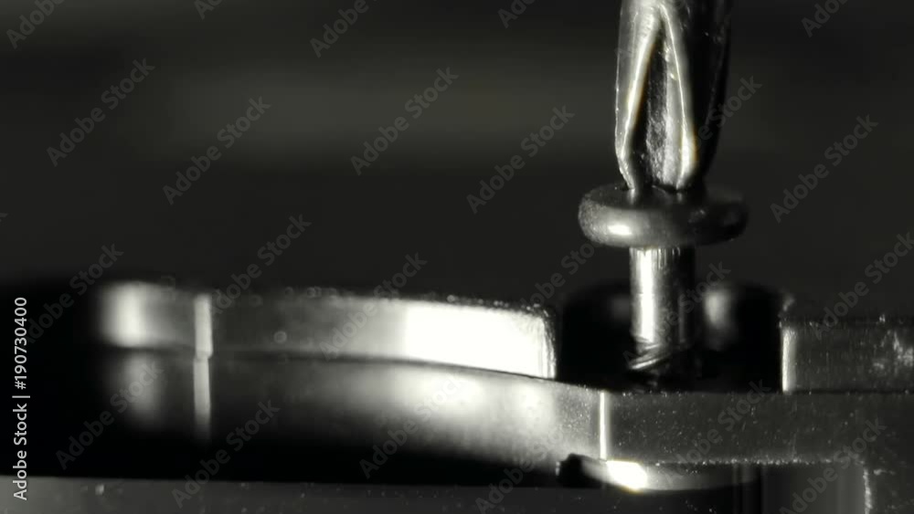 Screwdriver twists (unscrews) the black screw into the body of the device. Macro video Screwdriver twists (unscrews) the black screw into the body of the device. Macro video