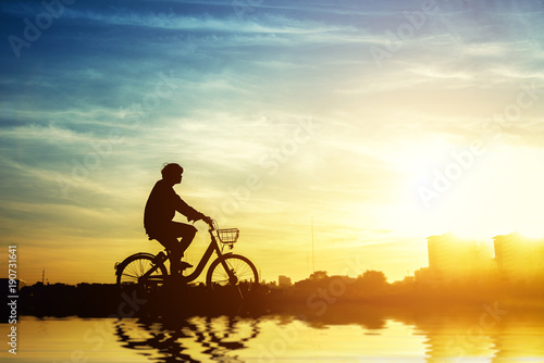 Silhouette of bicyclist riding the bike on a rocky trail at seaside on colorful sunset sky background. Active outdoors lifestyle for healthy concep