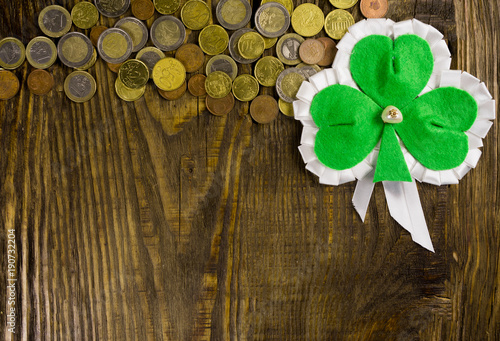 Clover leaf and a lot of coins on wooden background. Copy paste