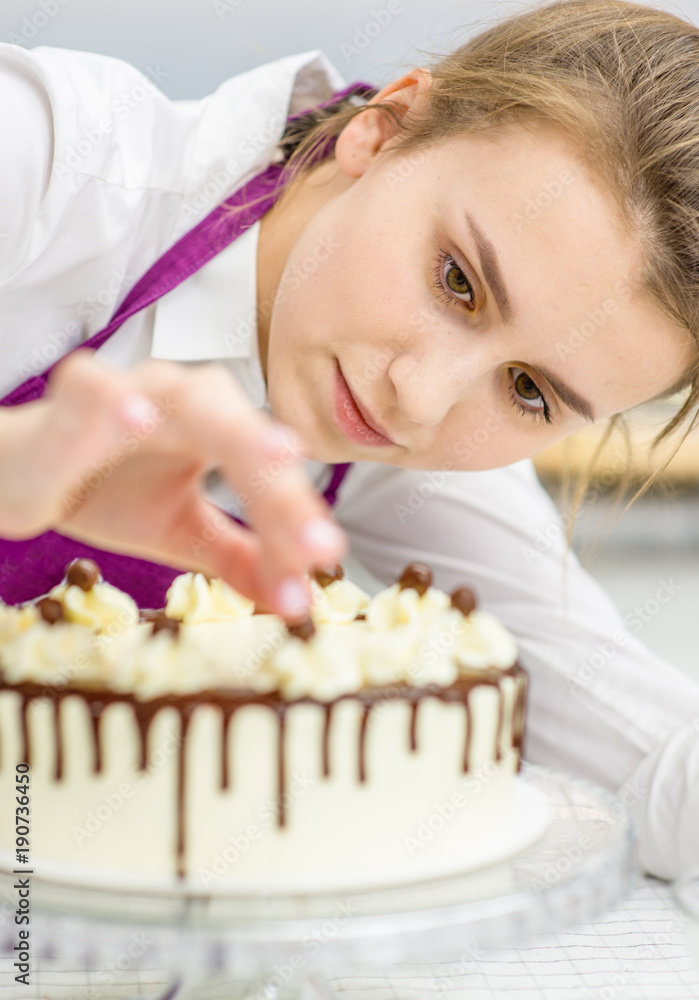 Young woman decorating chocolate cake in the kitchen Young woman decorating chocolate cake in the kitchen