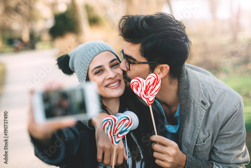 A happy guy and a girl hold a lollipop in their hands.