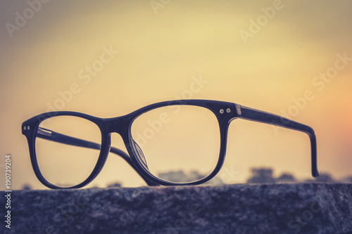  eyeglasses on table with sunset background