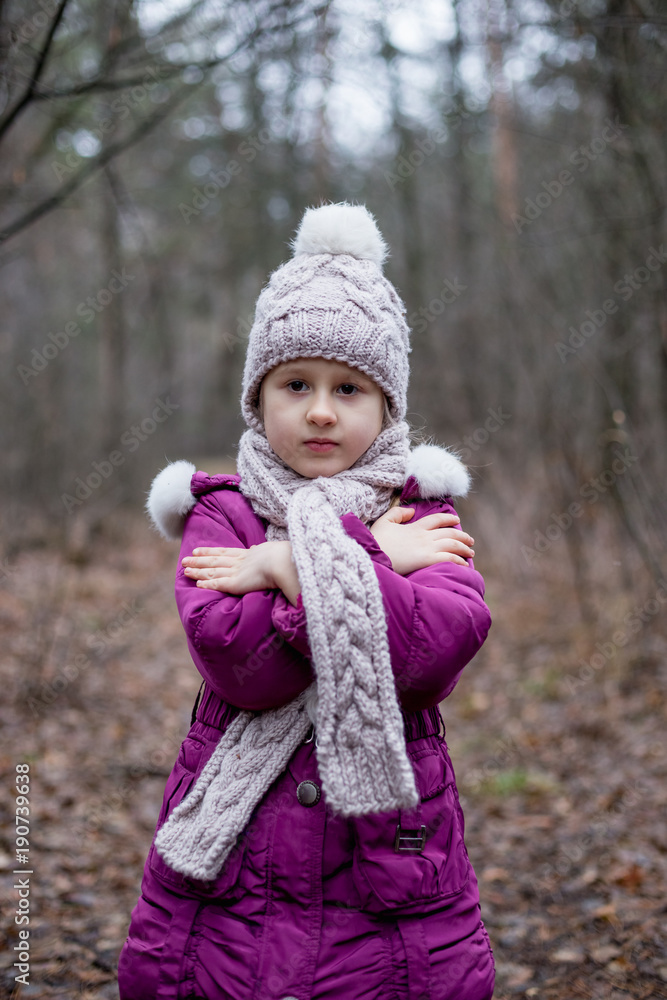 A little girl is standing in a forest on a path. A little girl is standing in a forest on a path.