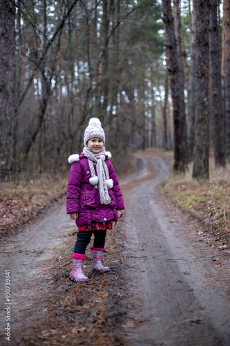 Little cute little girl posing on the road in the autumn forest.