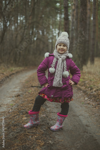 Little cute little girl posing on the road in the autumn forest.