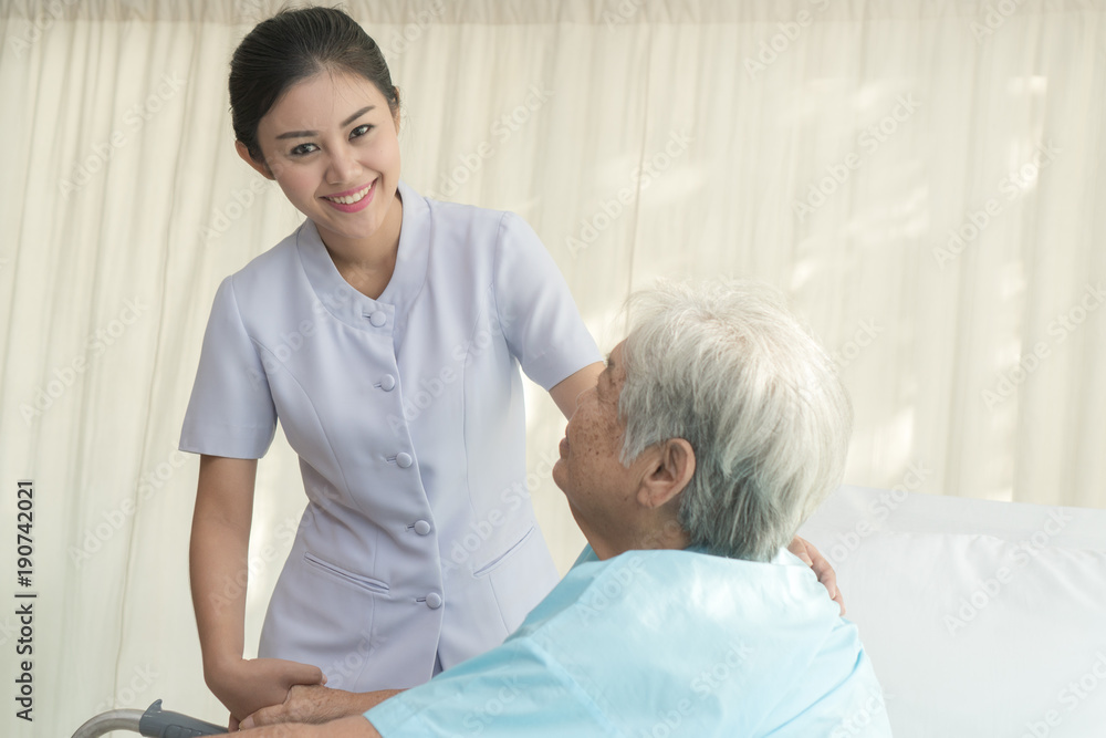 Obraz premium Cheerful asian nurse visiting elderly patient to check up after surgery in hospital for giving physical therapy and encouragement.