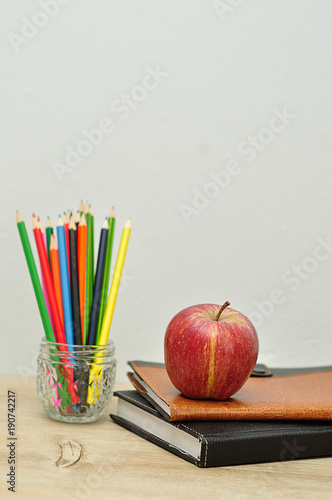 An apple displayed with books and coloring pencils © Marietjie Opperman