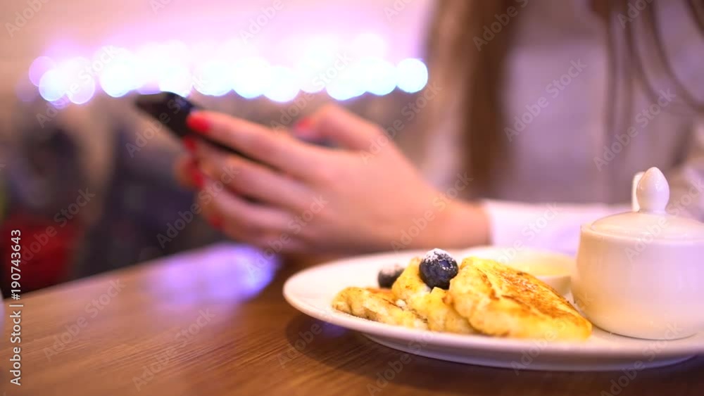 Woman using phone on the background of the food. Mobile phone in woman hand. Woman typing message on smartphone. Woman using phone on the background of the food. Mobile phone in woman hand. Woman typing message on smartphone.