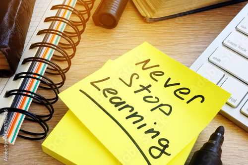 Never stop learning written on a memo stick. Lifelong learning concept. photo