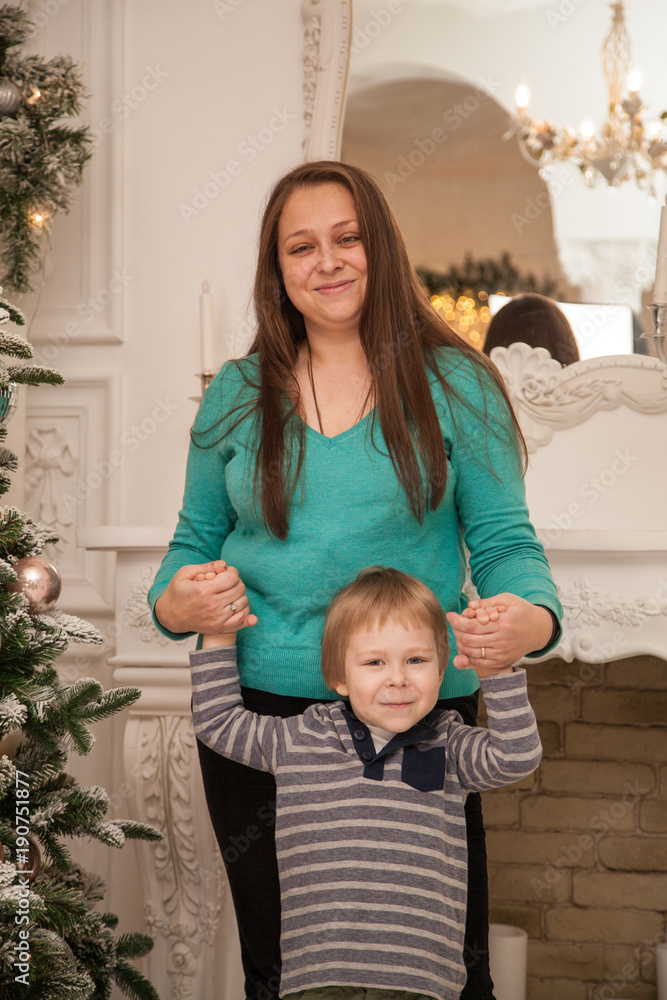 Mom and son on the background of a New Year tree and a fireplace Mom and son on the background of a New Year tree and a fireplace