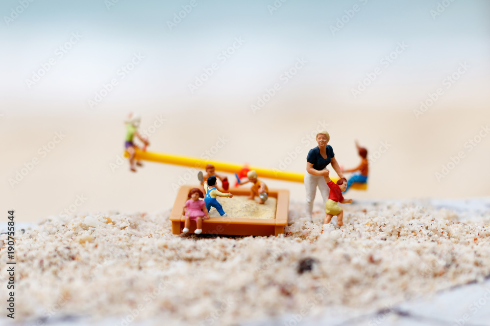 Obraz premium Miniature people: Children play on the swings on the beach with mother. Concept of happy family day.
