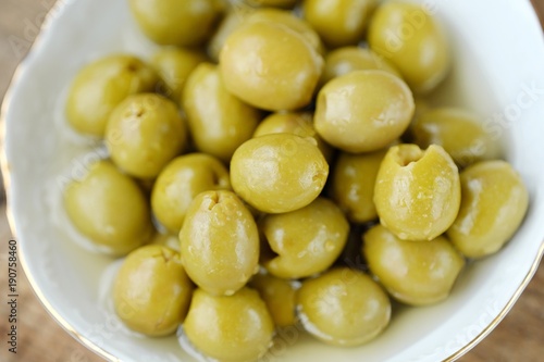 Delicious green olives in the bowl on the table  