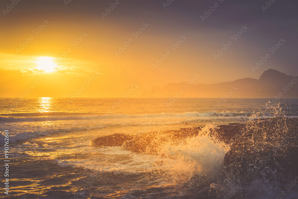 Golden sunset over the undulating sea on the mountain coast