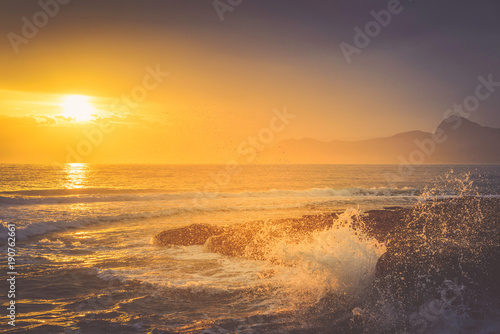 Golden sunset over the undulating sea on the mountain coast