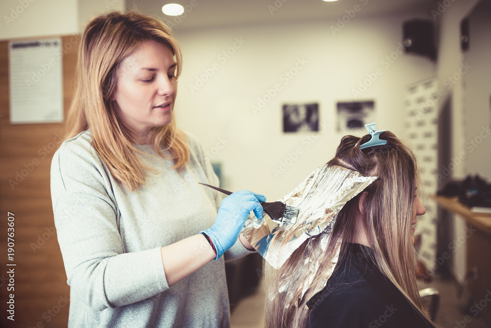 Premium Photo  Hairdresser is dying female hair, making hair highlights to  his client with a foil.