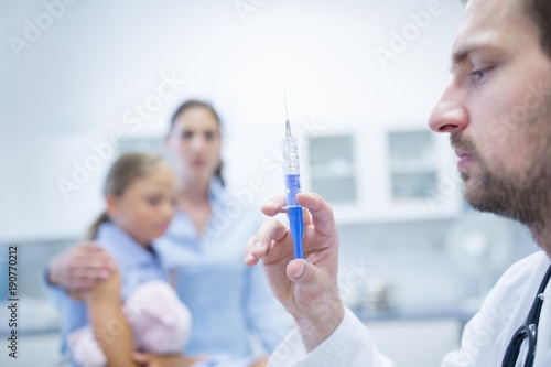 Doctor preparing injection for girl photo