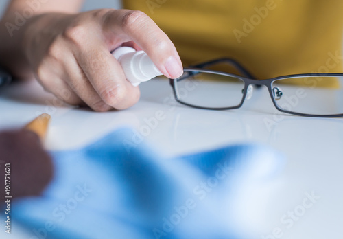Hand woman cleaning her glasses,Clean lenses of eyeglasses,Selective focus hand