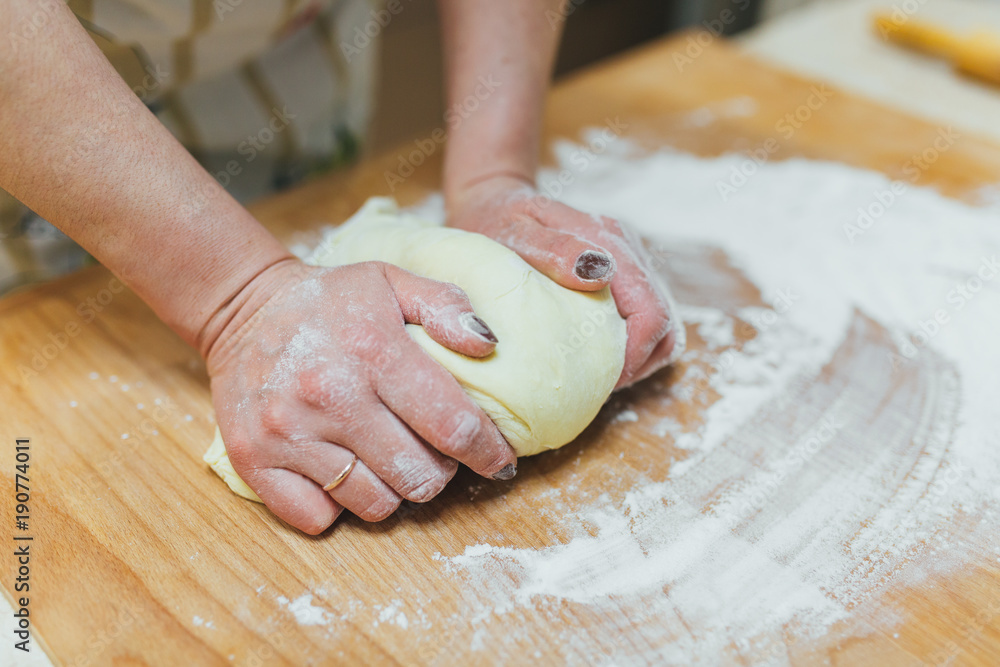 Making dough by female hands on wooden table background Making dough by female hands on wooden table background