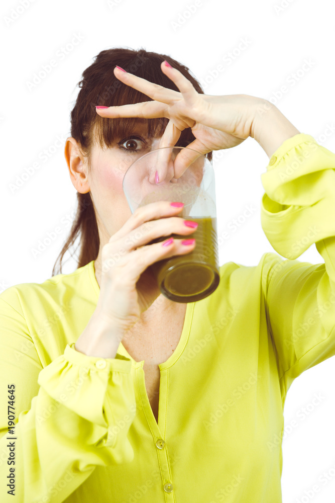Frau trinkt grünen Smoothie und hält sich Nase zu Frau trinkt grünen Smoothie und hält sich Nase zu
