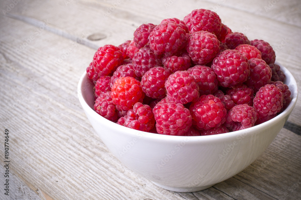 full bowl of juicy ripe raspberries, perfect colorful summer background with wood texture full bowl of juicy ripe raspberries, perfect colorful summer background with wood texture