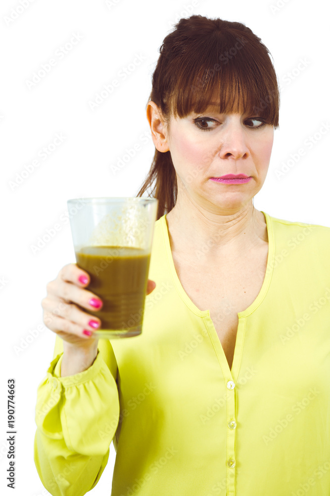 Frau hält grünen Smoothie und schaut skeptisch Frau hält grünen Smoothie und schaut skeptisch