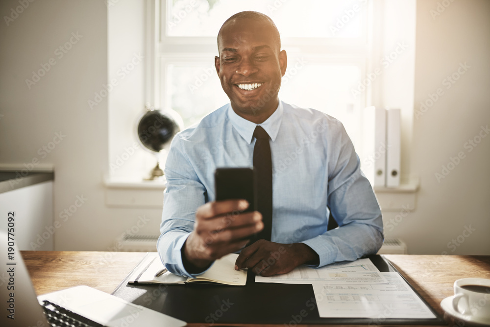Young businessman smiling at a text on his phone Young businessman smiling at a text on his phone