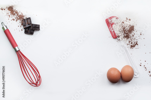 Bakery ingredients - flour, eggs, cocoa, chocolate on white table. Sweet pastry baking concept. Flat lay, copy space, top view