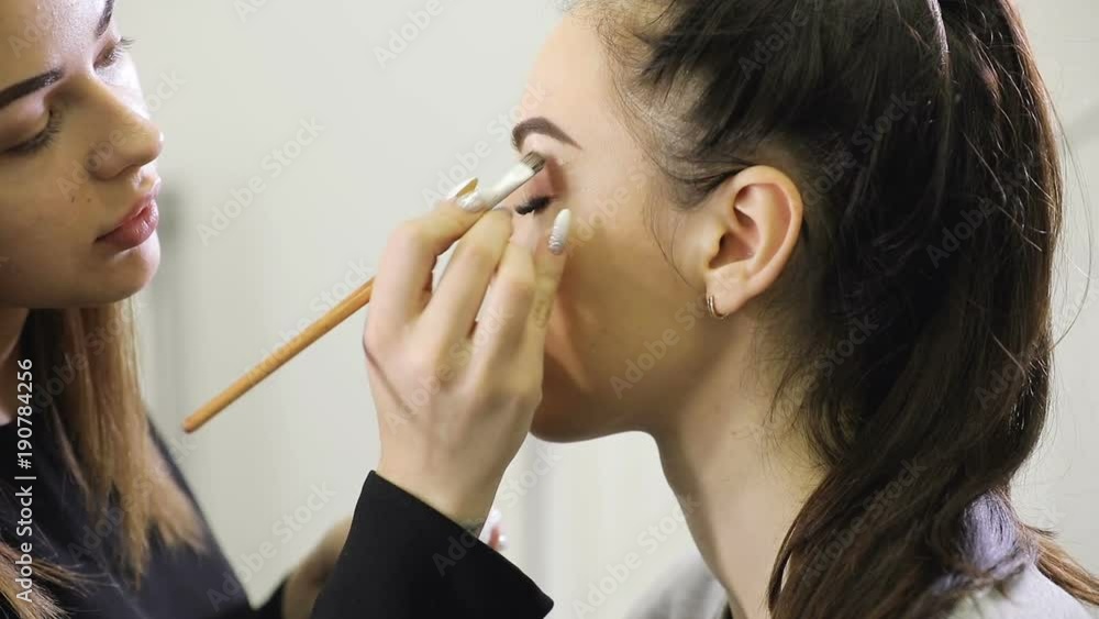 Close up of visagist doing makeup, coloring eyebrows with mascara Close up of visagist doing makeup, coloring eyebrows with mascara