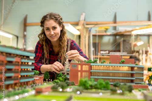 Billede på lærred Young woman looking at camera while finishing layout of new city district