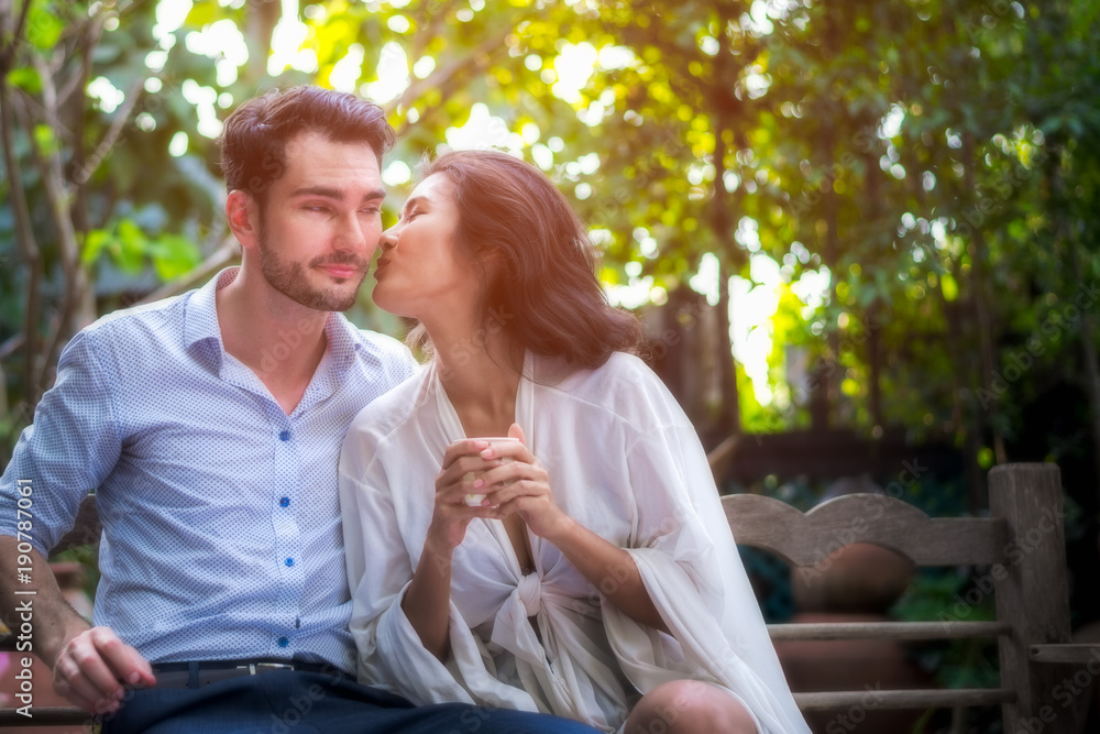 Naklejka premium Romantic Concept. Asian women and man happiness and romantic scene of love couples partners making eye contact and kiss in the garden at home for valentine day.