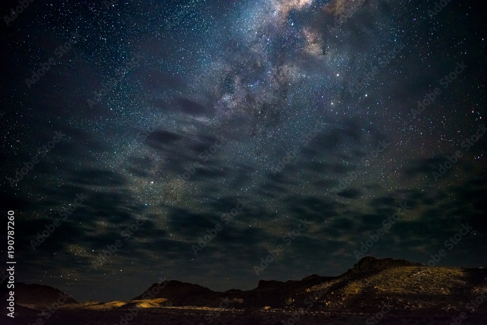 Milky Way arch, stars in the sky, the Namib desert in Namibia, Africa. Some scenic clouds.