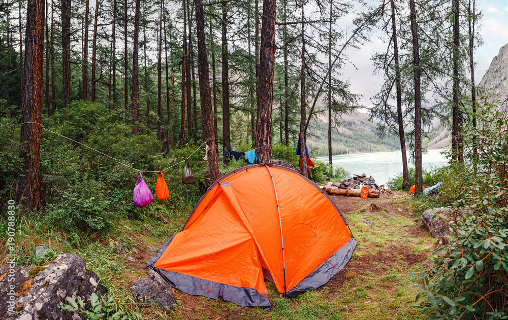 Camping Tent in the forest in front of mountain lake