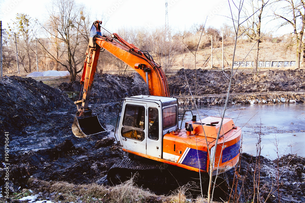 Excavation in the park. Excavator working on the lake. Excavation in the park. Excavator working on the lake.