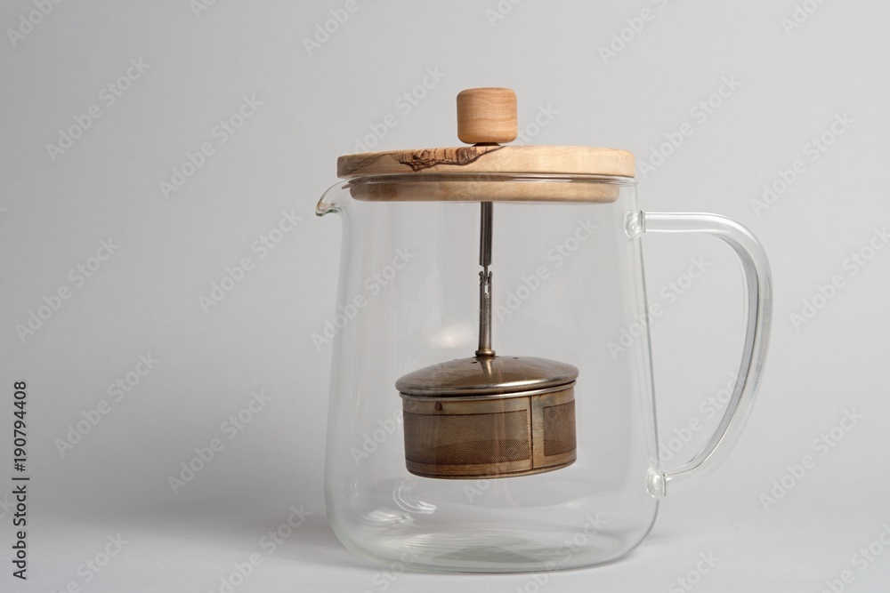 Empty glass teapot with wooden cap on light background Empty glass teapot with wooden cap on light background